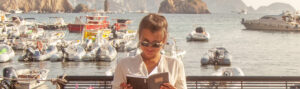 Ragazza legge un libro seduta su una panchina al porto di Ponza - Foto di WineDonuts da Adobe Stock